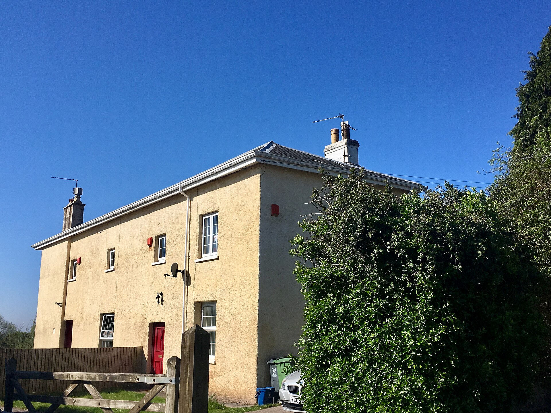 A cream-rendered two-storey listed house in Rhiwbina under a blue sky.