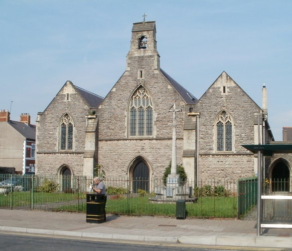 A grey stone Church in Wales church with a bell turret, seen across Splott Road.