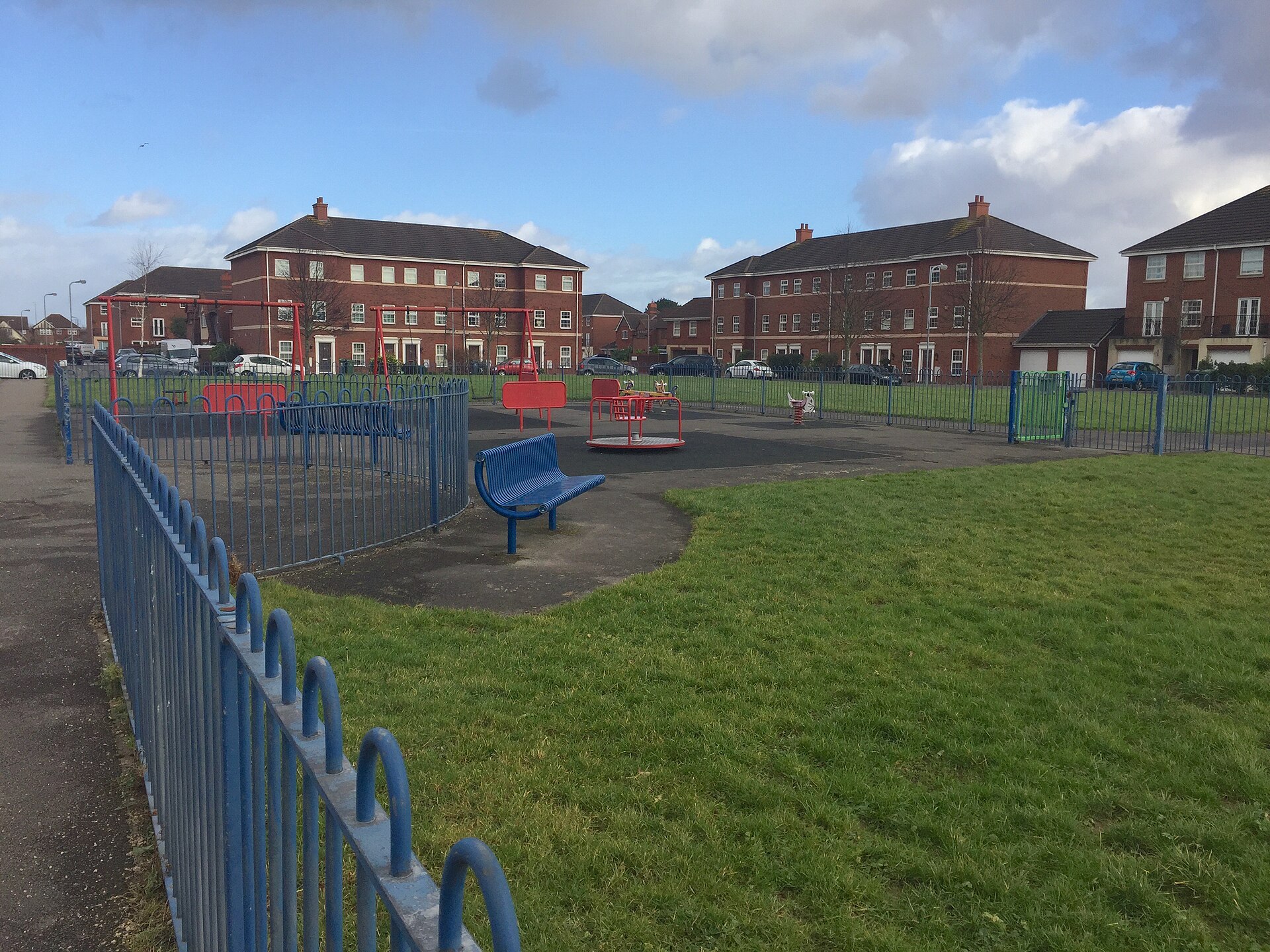 A children's play area on a green beside new red-brick houses at Pengam.