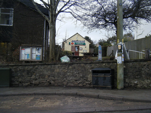 The post office in Peterston-super-Ely, seen beyond a stone wall and noticeboard.