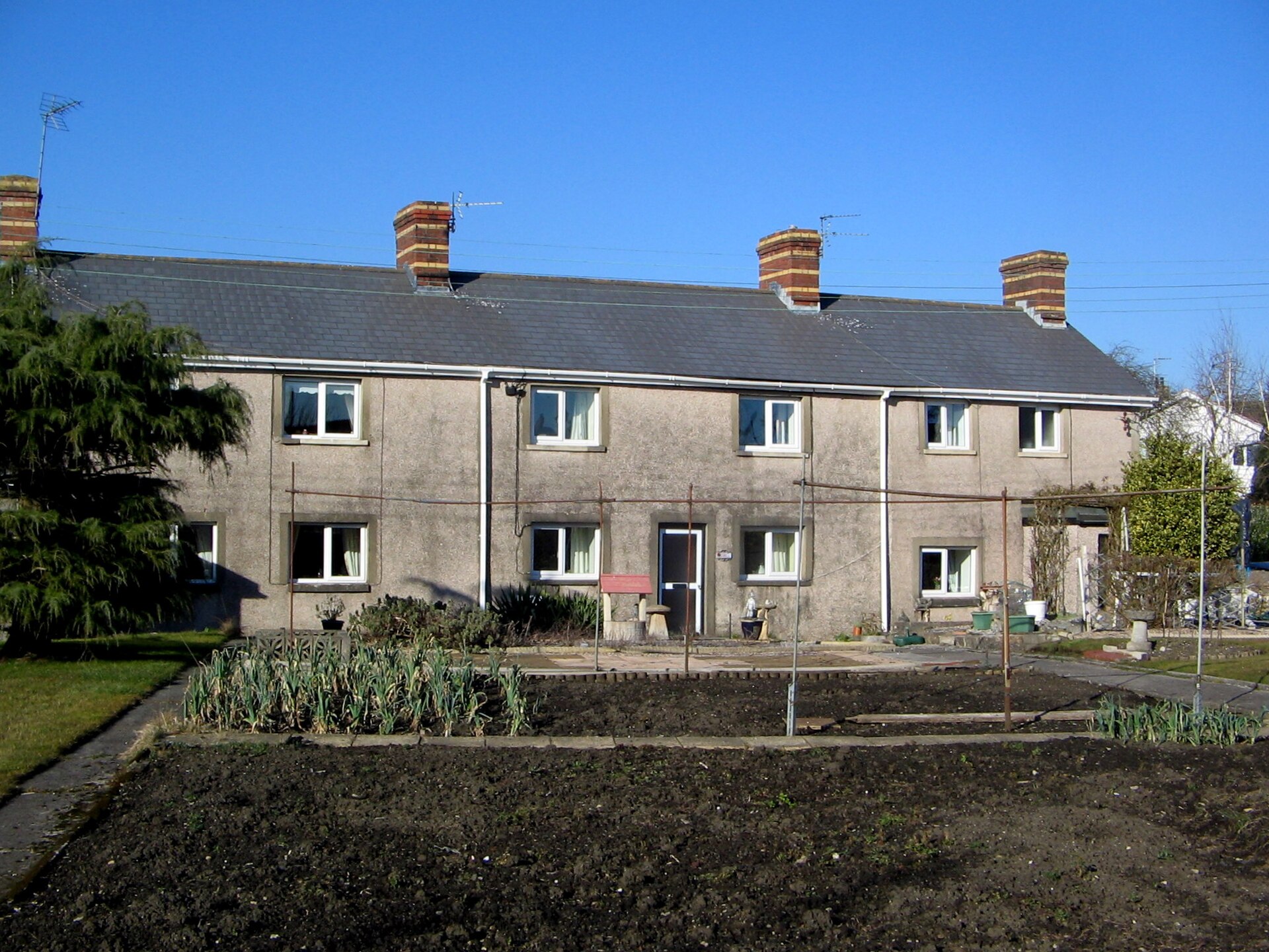 A row of stone workman's cottages in Treoes with a vegetable garden in front.